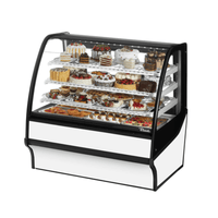 Curved glass refrigerated display case showcasing various pastries and desserts in a stylish bakery setting.